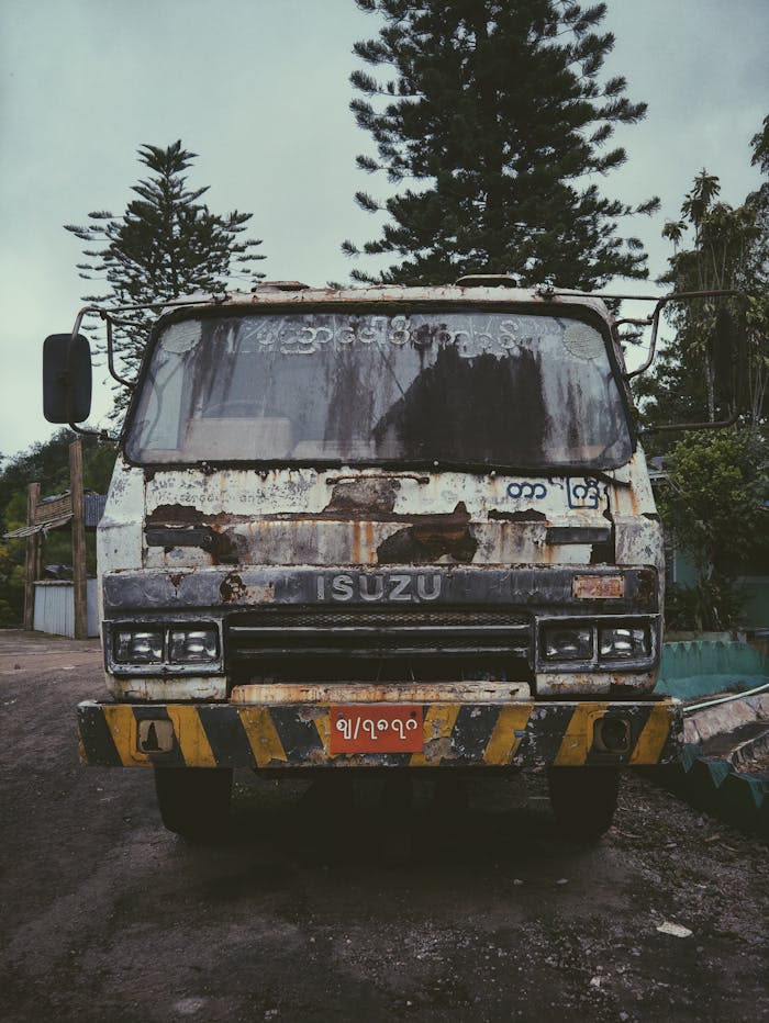 Front view of a weathered Isuzu truck parked outdoors, showcasing rustic and vintage appeal.