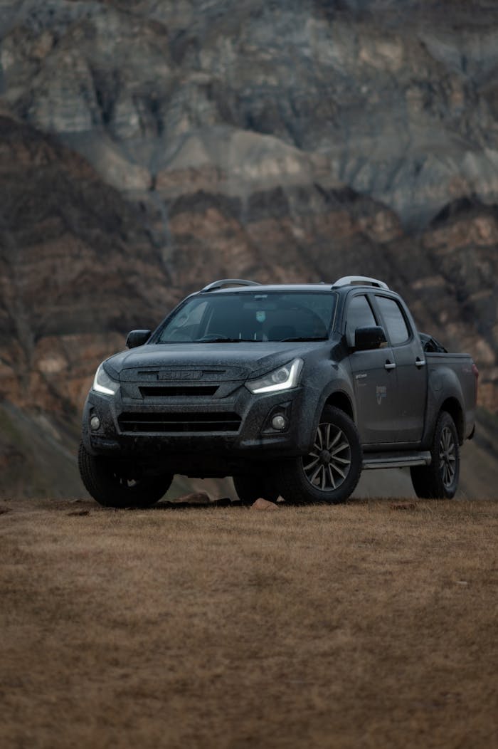 Isuzu pickup truck parked against the rugged mountain backdrop of Himachal Pradesh, India.